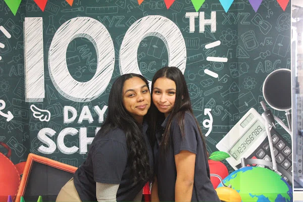 students posing in front of 100th day banner