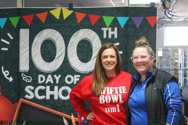 teachers posing in front of 100th day banner